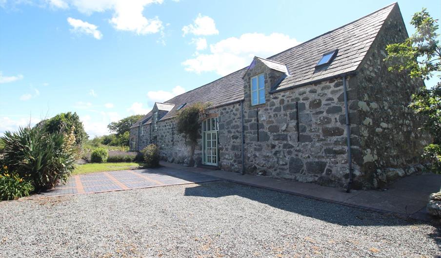 Photo of Ysgubor Degwm, a converted medieval barn on the Llyn Peninsula near Chwilog. Build from large irresgular stone this long barnhas a slate roof