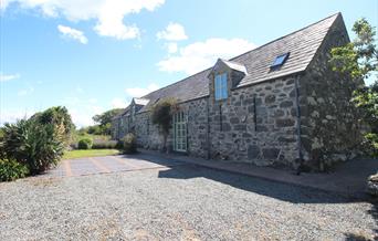 Photo of Ysgubor Degwm, a converted medieval barn on the Llyn Peninsula near Chwilog. Build from large irresgular stone this long barnhas a slate roof